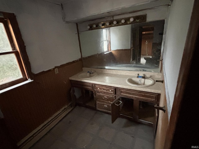 bathroom with double vanity, a wainscoted wall, tile patterned floors, and a sink