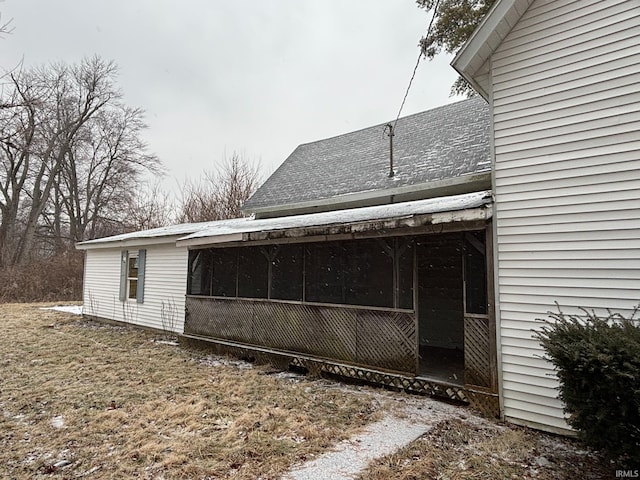 exterior space with a shingled roof and a sunroom