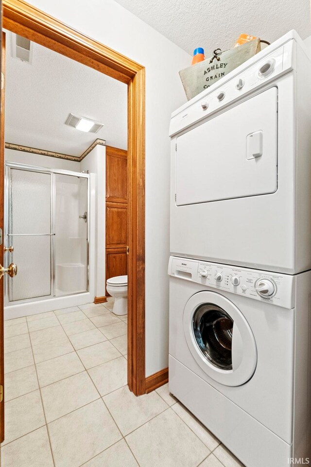 760 Ln 136 Turkey Lk, Hudson, IN 46747 - laundry room featuring light tile patterned floors, visible vents, laundry area, a textured ceiling, and stacked washer / dryer