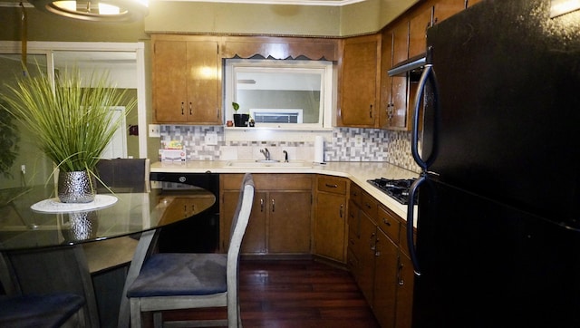 kitchen featuring a sink, decorative backsplash, brown cabinets, and black appliances
