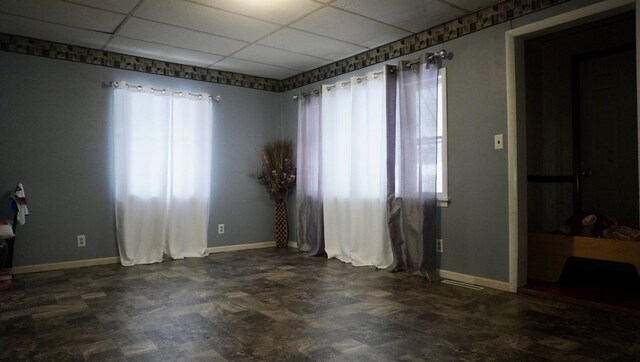 spare room featuring baseboards and a drop ceiling