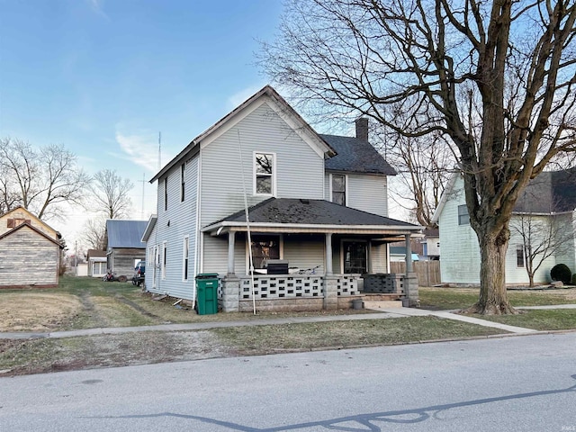 view of front of home featuring roof with shingles, covered porch, and a chimney