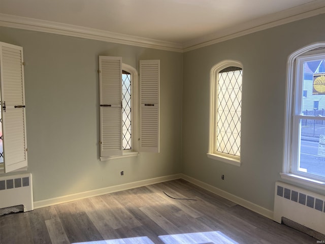 empty room with radiator, crown molding, and wood finished floors