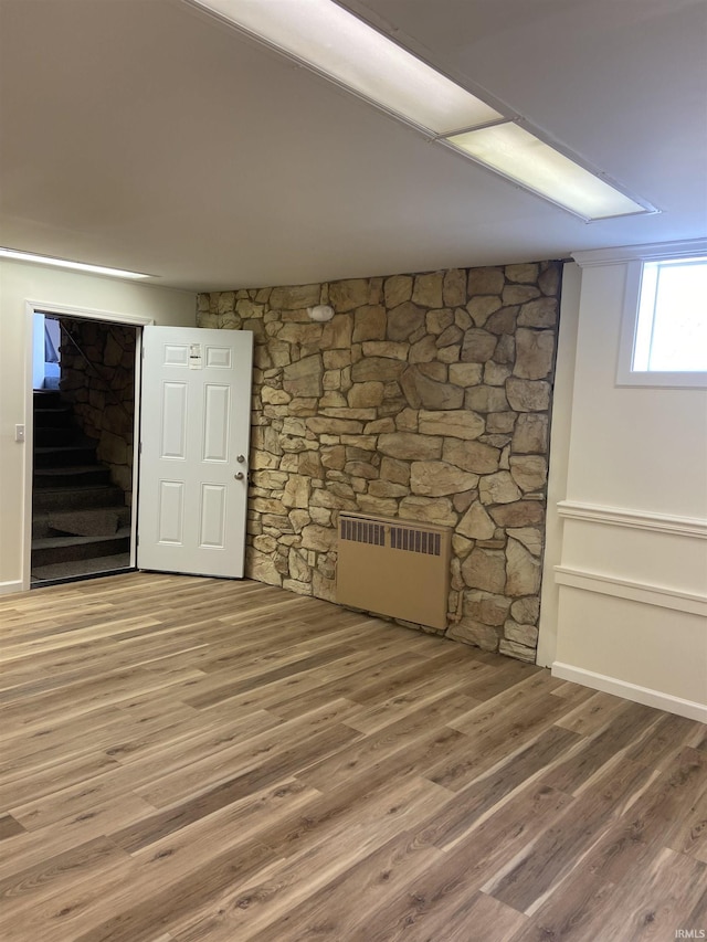basement with stairs, wood finished floors, and radiator