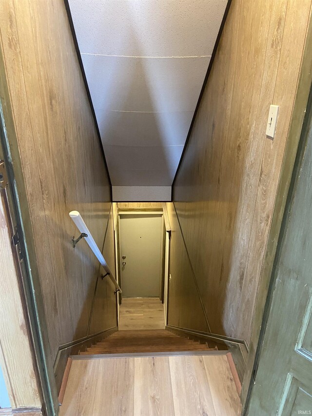 stairway featuring wooden walls and wood finished floors