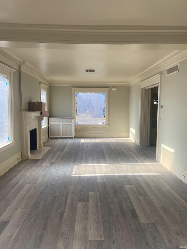 unfurnished living room featuring radiator heating unit, ornamental molding, a fireplace with flush hearth, and visible vents