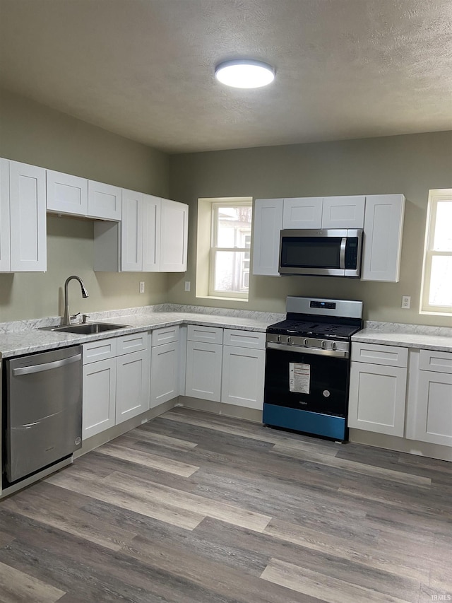 kitchen with white cabinets, a sink, a wealth of natural light, and appliances with stainless steel finishes