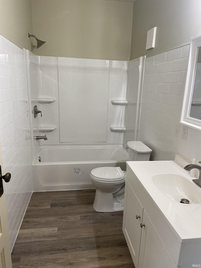 full bath featuring tile walls, wood finished floors, toilet, vanity, and  shower combination