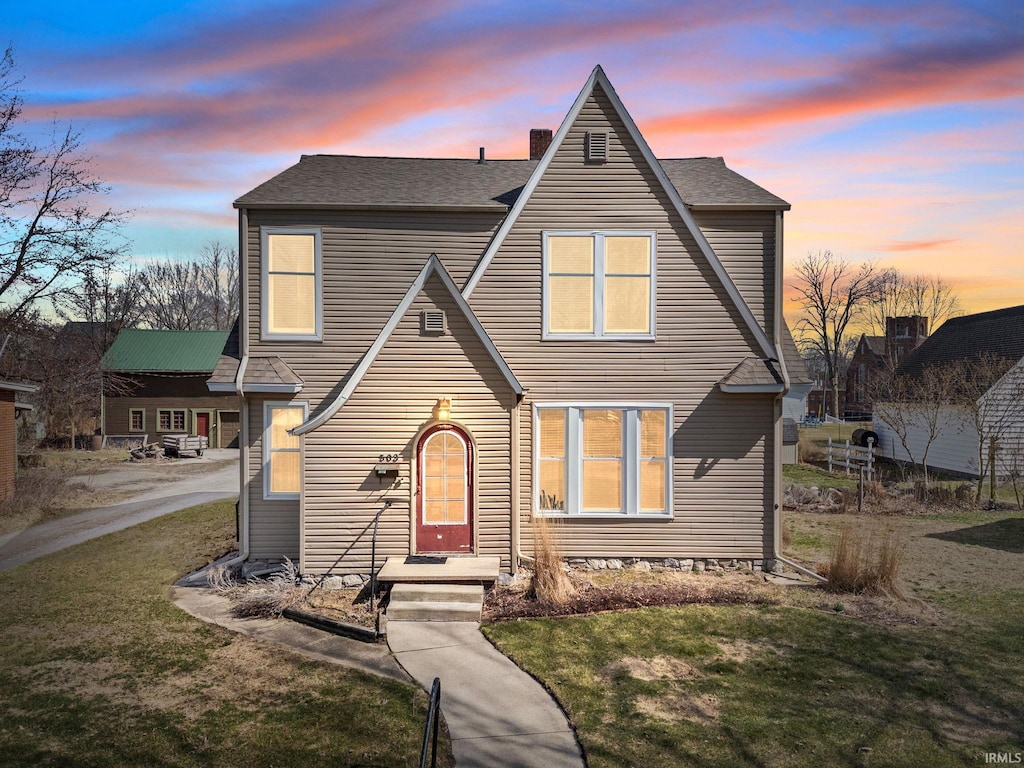 view of front of property with a chimney, a front lawn, and roof with shingles