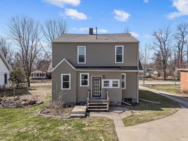 back of property with a lawn, roof with shingles, and a chimney