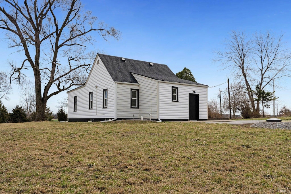 back of property featuring a lawn and roof with shingles