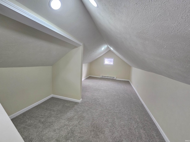 bonus room with a baseboard heating unit, vaulted ceiling, and a textured ceiling