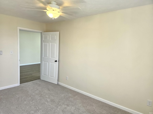 carpeted empty room with baseboards and a ceiling fan