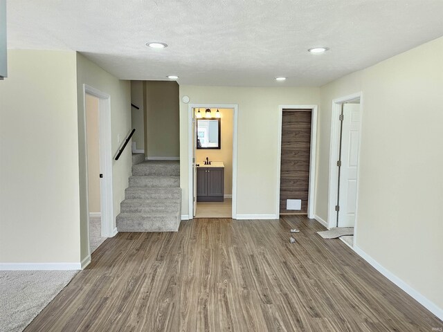unfurnished living room featuring baseboards, wood finished floors, stairs, and recessed lighting