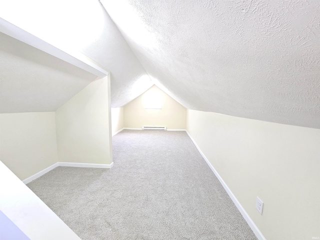 additional living space featuring vaulted ceiling, a textured ceiling, baseboards, carpet flooring, and visible vents