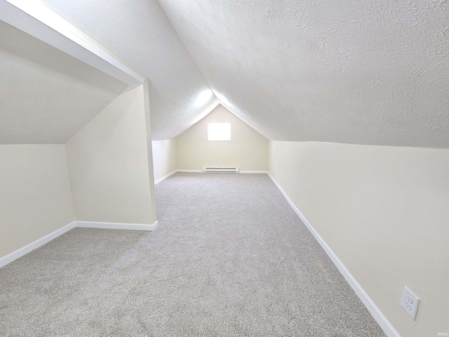 additional living space with carpet floors, a textured ceiling, lofted ceiling, and baseboard heating