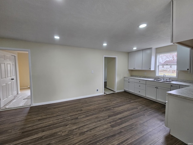 kitchen featuring a sink, light countertops, baseboards, dark wood-style flooring, and recessed lighting