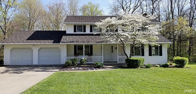 traditional-style home featuring a porch, an attached garage, a front lawn, and driveway