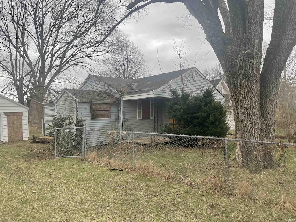 view of front of home with a fenced front yard, an outdoor structure, and a front lawn