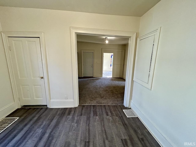 spare room featuring visible vents, baseboards, and dark wood-style floors