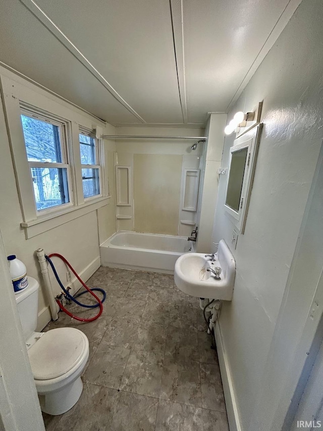 bathroom featuring toilet, shower / bathing tub combination, and baseboards
