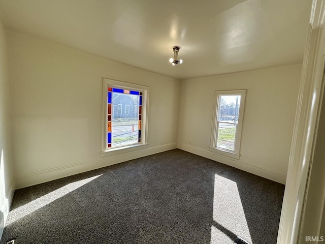 empty room with baseboards and dark colored carpet