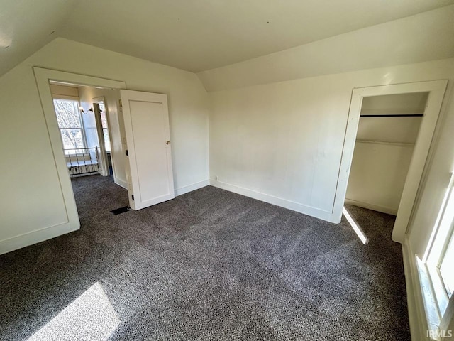 unfurnished bedroom featuring baseboards, lofted ceiling, and dark carpet