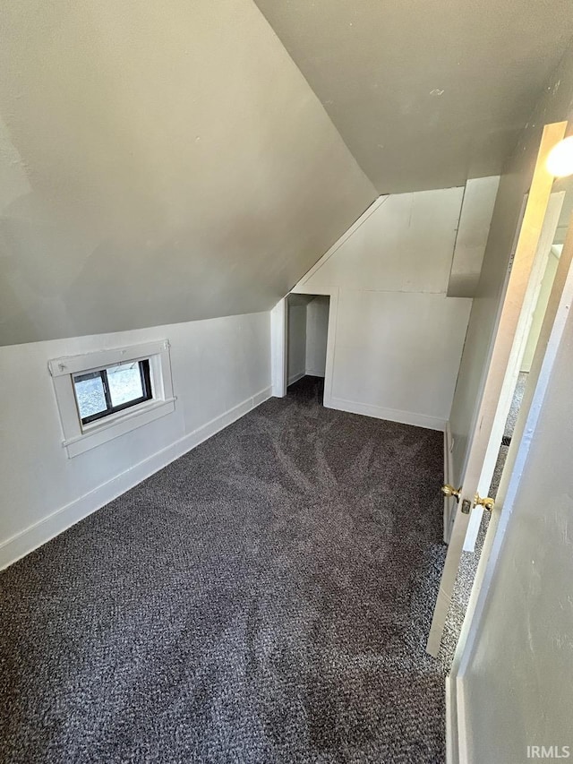 bonus room with baseboards, dark carpet, and vaulted ceiling