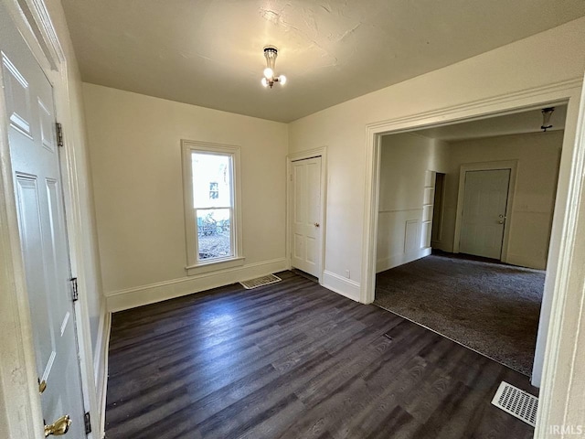 unfurnished bedroom with a closet, visible vents, dark wood-type flooring, and baseboards