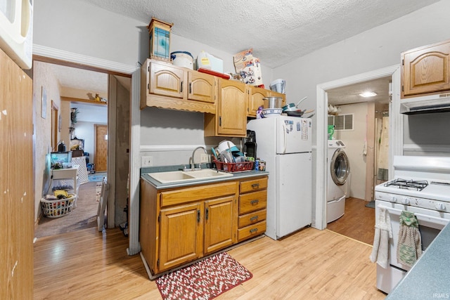 kitchen with white appliances, washer / dryer, light wood-style flooring, a sink, and under cabinet range hood