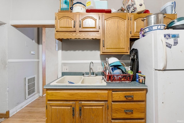 kitchen with visible vents, light countertops, freestanding refrigerator, light wood-style floors, and a sink