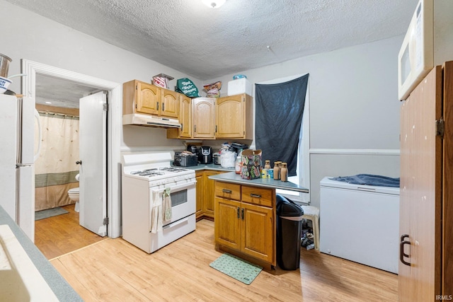 kitchen featuring white appliances, light countertops, light wood-style floors, under cabinet range hood, and a textured ceiling