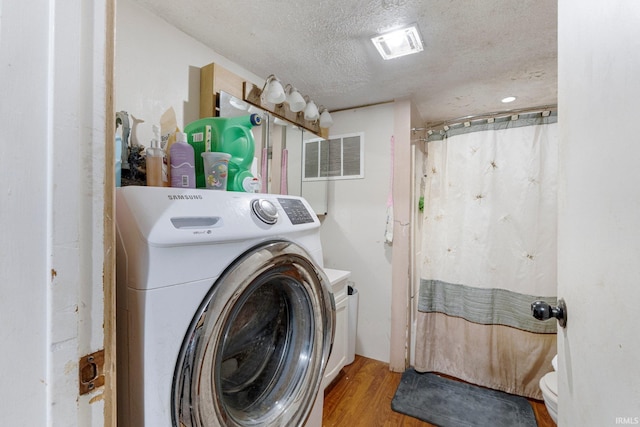 laundry area with visible vents, a textured ceiling, wood finished floors, washer / dryer, and laundry area