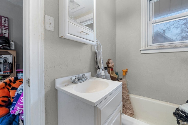 bathroom featuring a washtub, vanity, and a textured wall