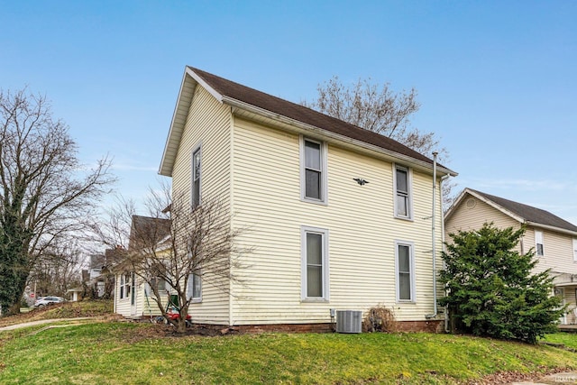 rear view of property with central AC and a yard