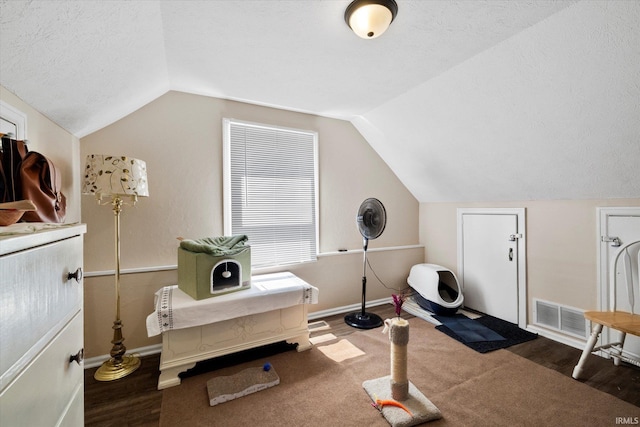 exercise area with visible vents, baseboards, lofted ceiling, wood finished floors, and a textured ceiling