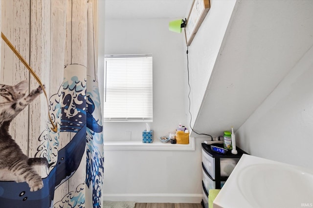 full bath with a shower with shower curtain, baseboards, and a sink