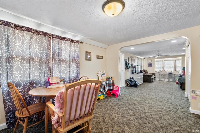 dining room featuring arched walkways, a textured ceiling, carpet floors, and a ceiling fan