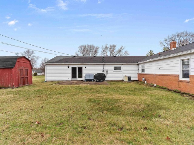 rear view of house with a storage unit, a lawn, a patio, cooling unit, and an outdoor structure