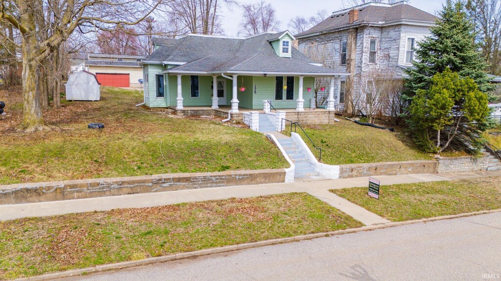 view of front of property with a porch, a front yard, and roof with shingles