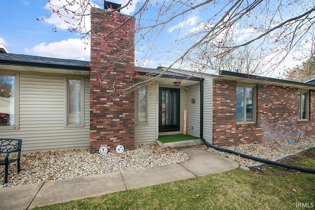 view of front of house with brick siding and a chimney