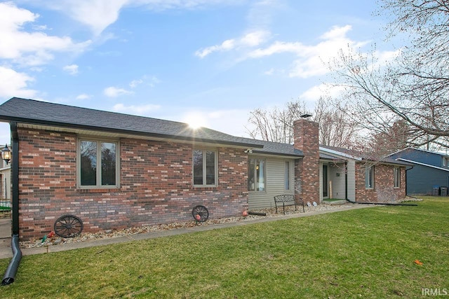 view of front of house with brick siding, roof with shingles, a chimney, and a front yard