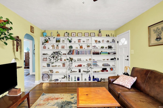 living room with arched walkways and wood finished floors