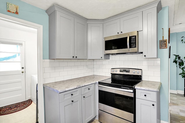 kitchen with light countertops, stainless steel appliances, and decorative backsplash