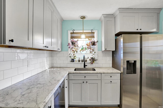 kitchen featuring backsplash, a sink, stainless steel fridge with ice dispenser, light stone countertops, and dishwashing machine