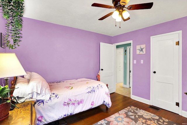 bedroom featuring baseboards, visible vents, ceiling fan, and wood finished floors