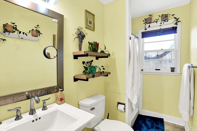 bathroom with baseboards, a sink, and toilet