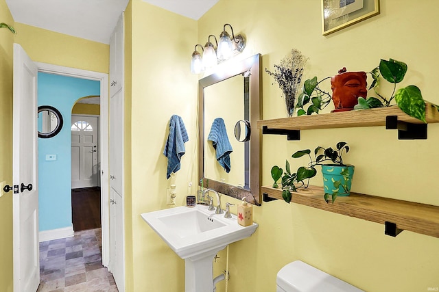 half bathroom featuring baseboards and toilet