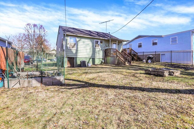 rear view of house featuring a lawn, cooling unit, fence, and a vegetable garden