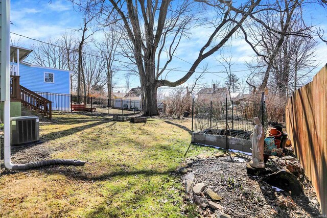 view of yard with a fenced backyard, a garden, and central AC